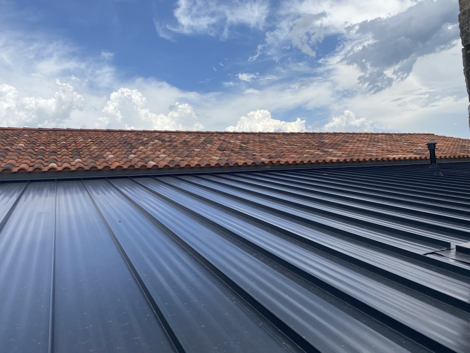 Dark standing seam metal meeting terracotta tile