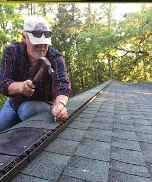 Robbie Reece nailing ridge vent on a shingle roof